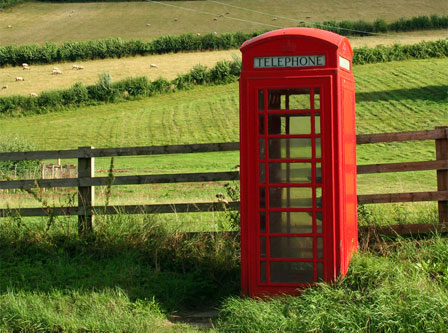 Red phone box in front of a field